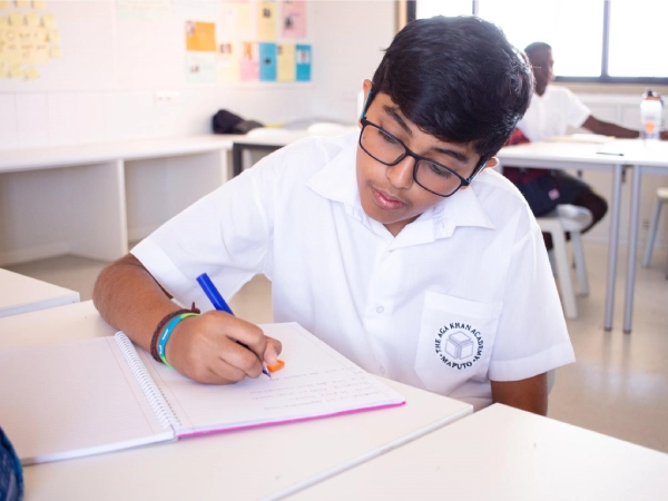An AKA Maputo student works on an assignment inside a classroom.